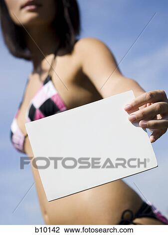Stock Image - Close-up of a young woman holding a blank sign. Fotosearch
