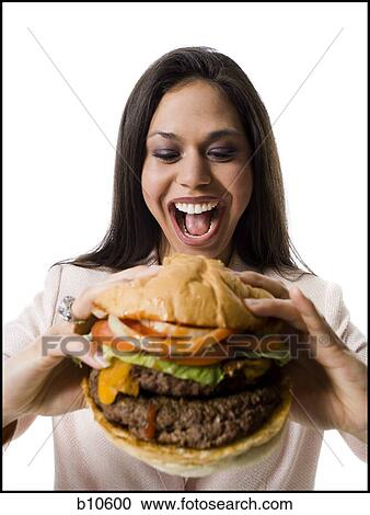 Stock Image - Close-up of a young woman holding a hamburger. Fotosearch