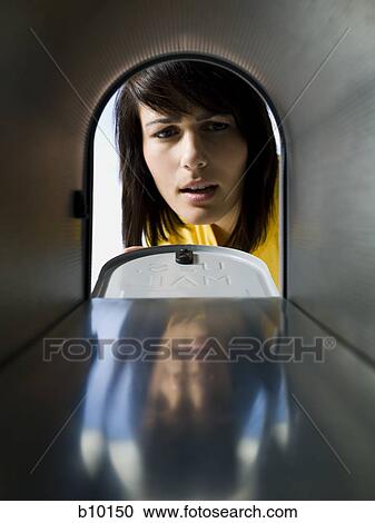 Stock Image - Close-up of a young woman looking at an empty mailbox. Fotosearch