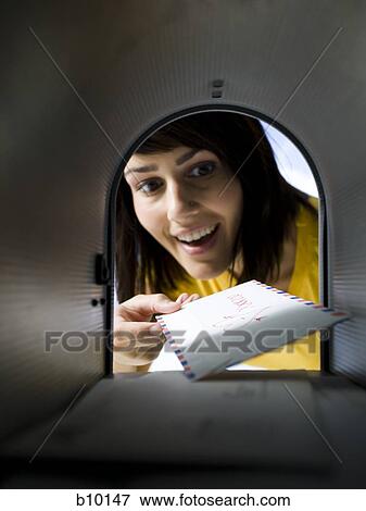 Stock Photo - Close-up of a young woman looking at mail in a mailbox. Fotosearch