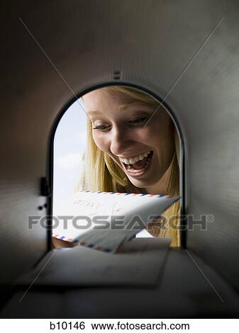 Close-up of a young woman looking at mail in a mailbox View Large Photo Image Stock Photograph - Close-up of a young woman looking at mail in a mailbox. Fotosearch