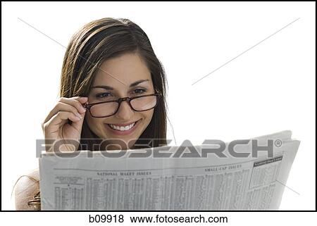 Stock Photo - Close-up of a young woman reading a newspaper and smiling. Fotosearch