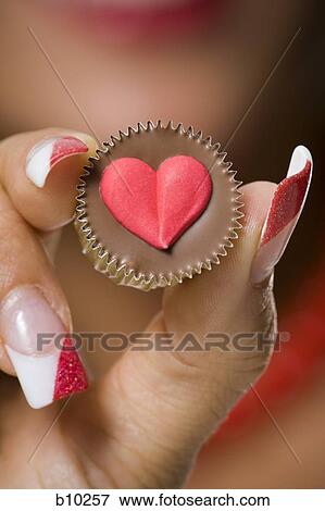 Close-up of a young woman's hand holding a chocolate View Large Photo Image Stock Photo - Close-up of a young woman's hand holding a chocolate. Fotosearch