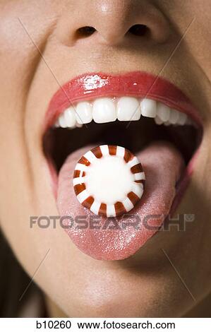 Stock Image - Close-up of candy on a young woman's tongue. Fotosearch