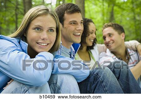 Close-up of two young women and two young men sitting and smiling View Large Photo Image Stock Photo - Close-up of two young women and two young men sitting and smiling. Fotosearch