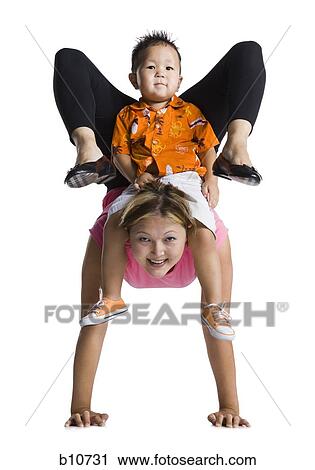 Stock Image - Contortionist mother with young son on back. Fotosearch