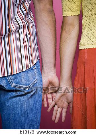 Couple holding hands rear view mid section View Large Photo Image Stock Image - Couple holding hands rear view mid section. Fotosearch