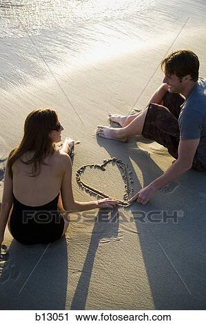 Couple on beach drawing valentines in sand View Large Photo Image Stock Image - Couple on beach drawing valentines in sand. Fotosearch