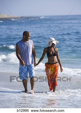 Stock Photography - Couple walking hand in hand on beach. Fotosearch