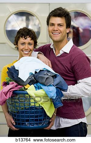 Couple with clothing in laundry basket at Laundromat smiling View Large Photo Image Picture - Couple with clothing in laundry basket at Laundromat smiling. Fotosearch
