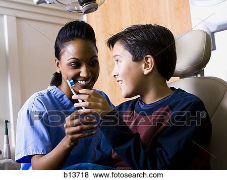 Stock Photo - Dental hygienist giving boy toothbrush. Fotosearch