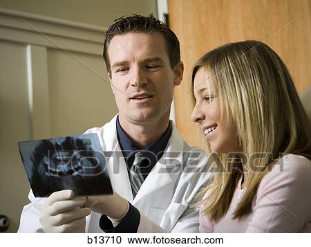 Dentist looking at x-rays with girl View Large Photo Image Stock Image - Dentist looking at x-rays with girl. Fotosearch
