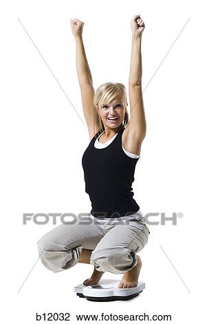 Stock Image - Dieting woman standing on bathroom scale. Fotosearch