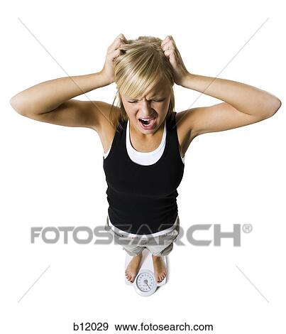 Stock Photo - Dieting woman standing on bathroom scale. Fotosearch