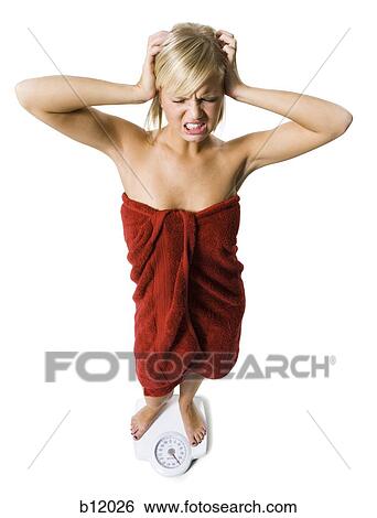 Stock Photograph - Dieting woman standing on bathroom scale. Fotosearch