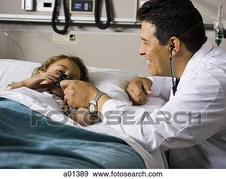 Stock Photo - Doctor with stethoscope examining young girl in hospital. Fotosearch