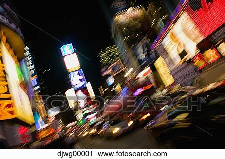 Stock Image - Downtown city at night with neon signs and motion blur. Fotosearch