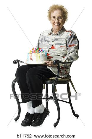 Stock Image - Elderly woman on her birthday with cake. Fotosearch
