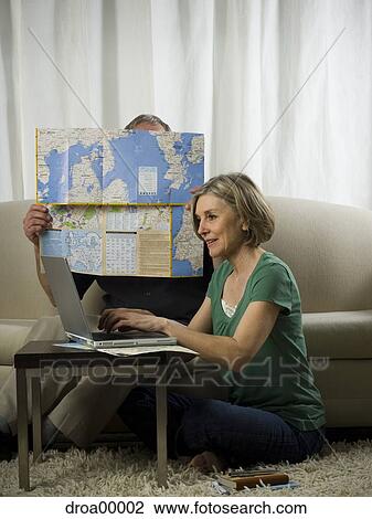 Elderly woman sitting in front of a laptop with an elderly man holding a map View Large Photo Image Stock Image - Elderly woman sitting in front of a laptop with an elderly man holding a map. Fotosearch
