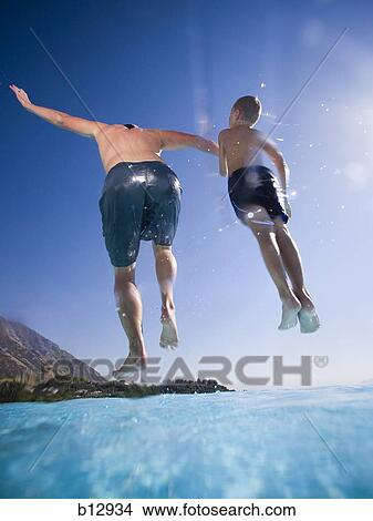 Father and son jumping into swimming pool View Large Photo Image Picture - Father and son jumping into swimming pool. Fotosearch