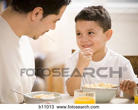 Stock Image - Father and young son having breakfast together. Fotosearch