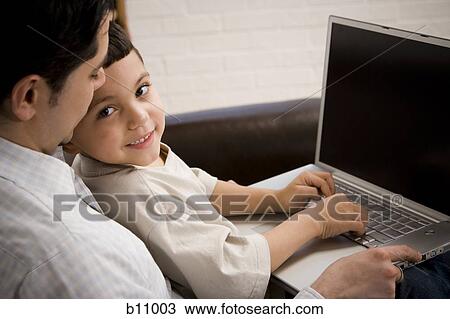 Stock Image - Father and young son working on laptop computer. Fotosearch
