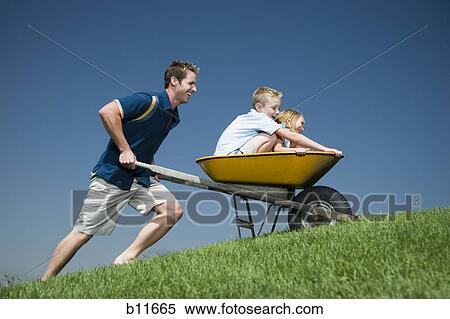 Father pushing son and daughter in a wheelbarrow View Large Photo Image Stock Photography - Father pushing son and daughter in a wheelbarrow. Fotosearch