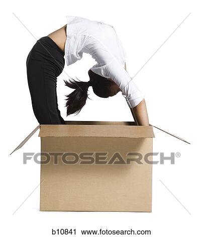 Stock Image - Female contortionist businesswoman inside cardboard box. Fotosearch