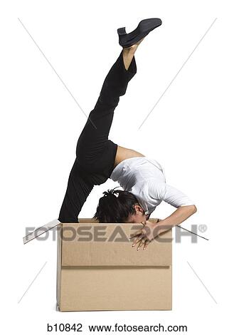 Stock Image - Female contortionist businesswoman inside cardboard box. Fotosearch