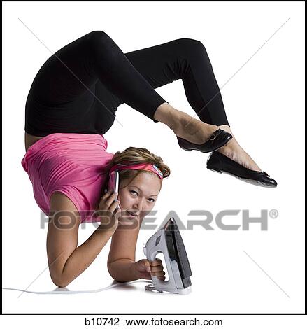 Stock Image - Female contortionist talking on phone and ironing. Fotosearch