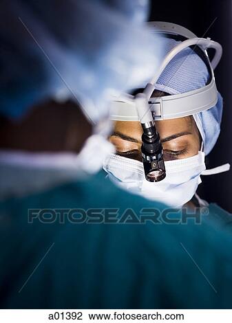 Female doctor in scrubs with head light in surgery View Large Photo Image Stock Image - Female doctor in scrubs with head light in surgery. Fotosearch