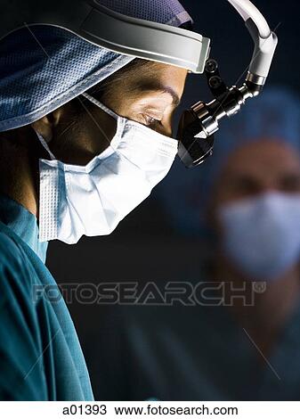 Female doctor in scrubs with head light in surgery View Large Photo Image Stock Image - Female doctor in scrubs with head light in surgery. Fotosearch
