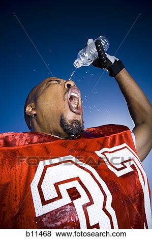 Stock Photo - Football player cooling off with water. Fotosearch