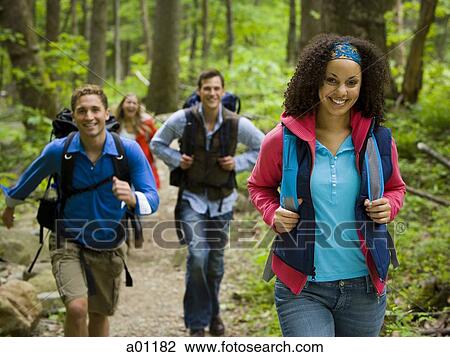 Stock Image - Four young adults hiking in the forest. Fotosearch