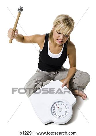 Frustrated dieting woman smashing bathroom scale with a hammer View Large Photo Image Stock Image - Frustrated dieting woman smashing bathroom scale with a hammer. Fotosearch