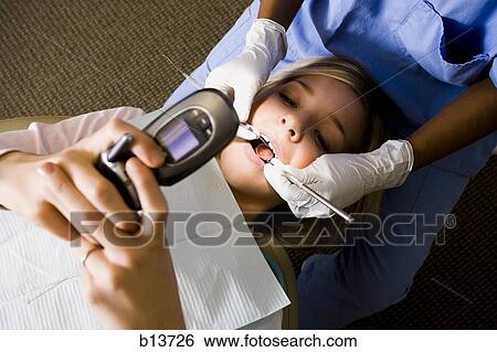 Stock Photograph - Girl having dental exam holding cell phone. Fotosearch