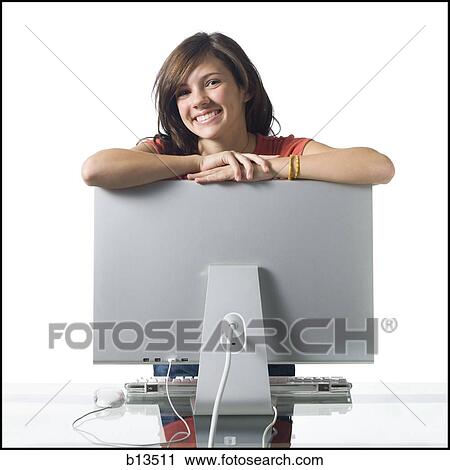 Stock Image - Girl leaning on computer monitor smiling. Fotosearch