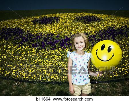 Girl on a hill holding happy face balloon View Large Photo Image Picture - Girl on a hill holding happy face balloon. Fotosearch