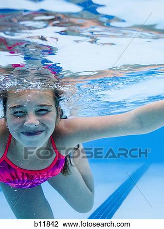 Stock Image - Girl swimming underwater in pool. Fotosearch