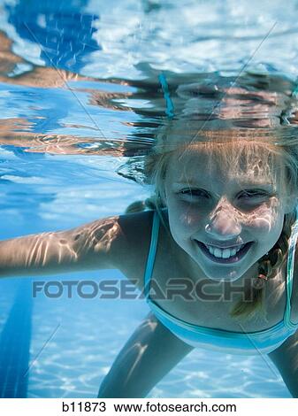 Stock Image - Girl swimming underwater in pool. Fotosearch