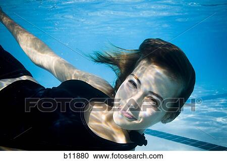 Stock Image - Girl swimming underwater in pool. Fotosearch