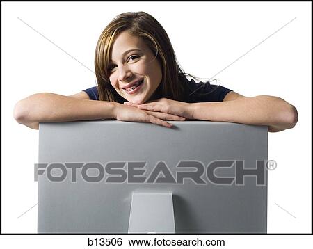 Stock Photograph - Girl with braces leaning on computer monitor smiling. Fotosearch