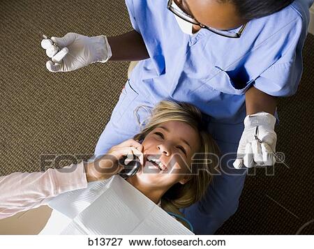 Girl with dental hygienist talking on cell phone View Large Photo Image Stock Photo - Girl with dental hygienist talking on cell phone. Fotosearch