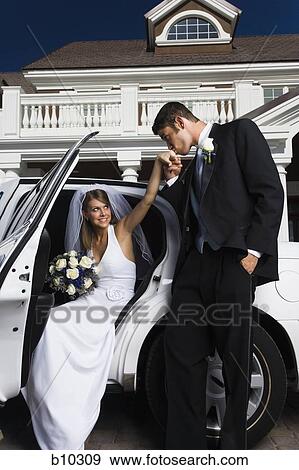Stock Photo - Groom kissing his bride's hand and getting out of a car. Fotosearch