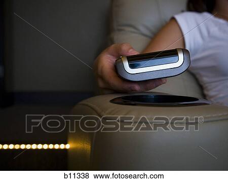 Hand holding remote control in home theater View Large Photo Image Stock Photo - Hand holding remote control in home theater. Fotosearch