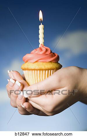 Hands holding a cupcake with one birthday candle View Large Photo Image Stock Photo - Hands holding a cupcake with one birthday candle. Fotosearch