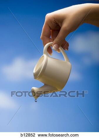 Stock Image - Last drop of water coming from watering can. Fotosearch