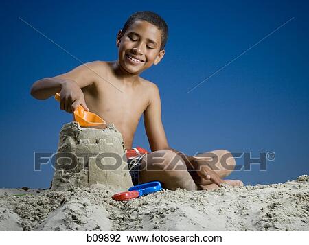 Low angle view of a boy making a sand castle View Large Photo Image Stock Image - Low angle view of a boy making a sand castle. Fotosearch