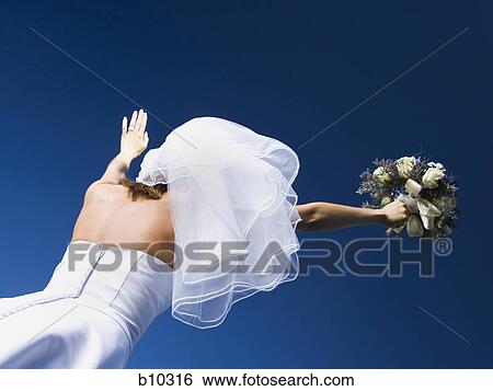 Low angle view of a bride holding a bouquet of flowers with her arms raised View Large Photo Image Stock Photograph - Low angle view of a bride holding a bouquet of flowers with her arms raised. Fotosearch