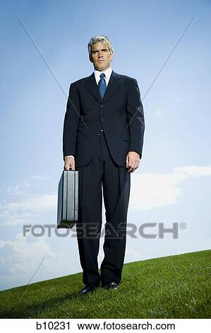 Low angle view of a businessman holding a briefcase View Large Photo Image Stock Image - Low angle view of a businessman holding a briefcase. Fotosearch